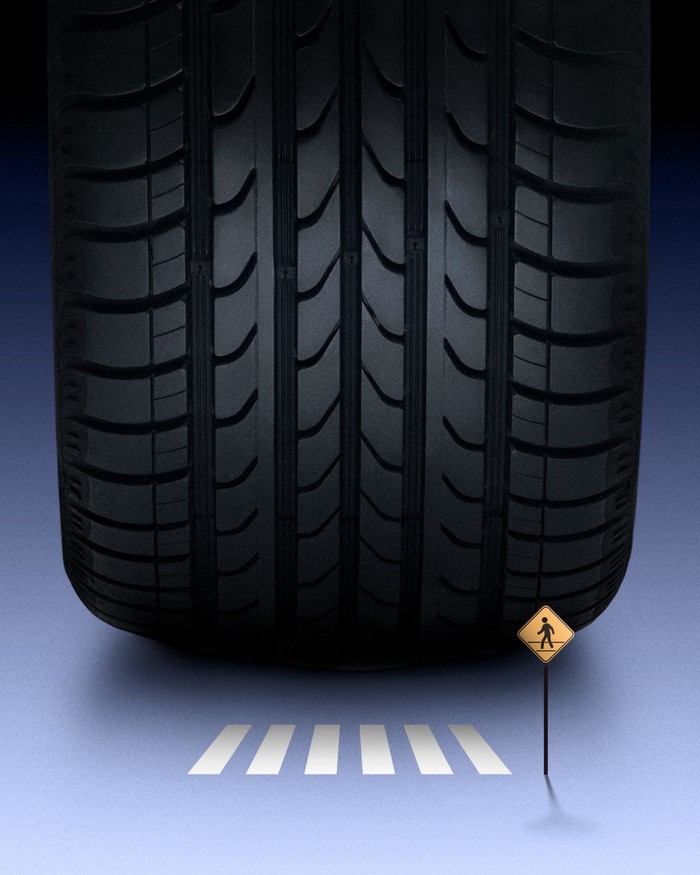 Photo illustration of giant car tire driving toward a tiny pedestrian crosswalk