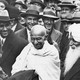 A black and white photograph of Gandhi in a crowd