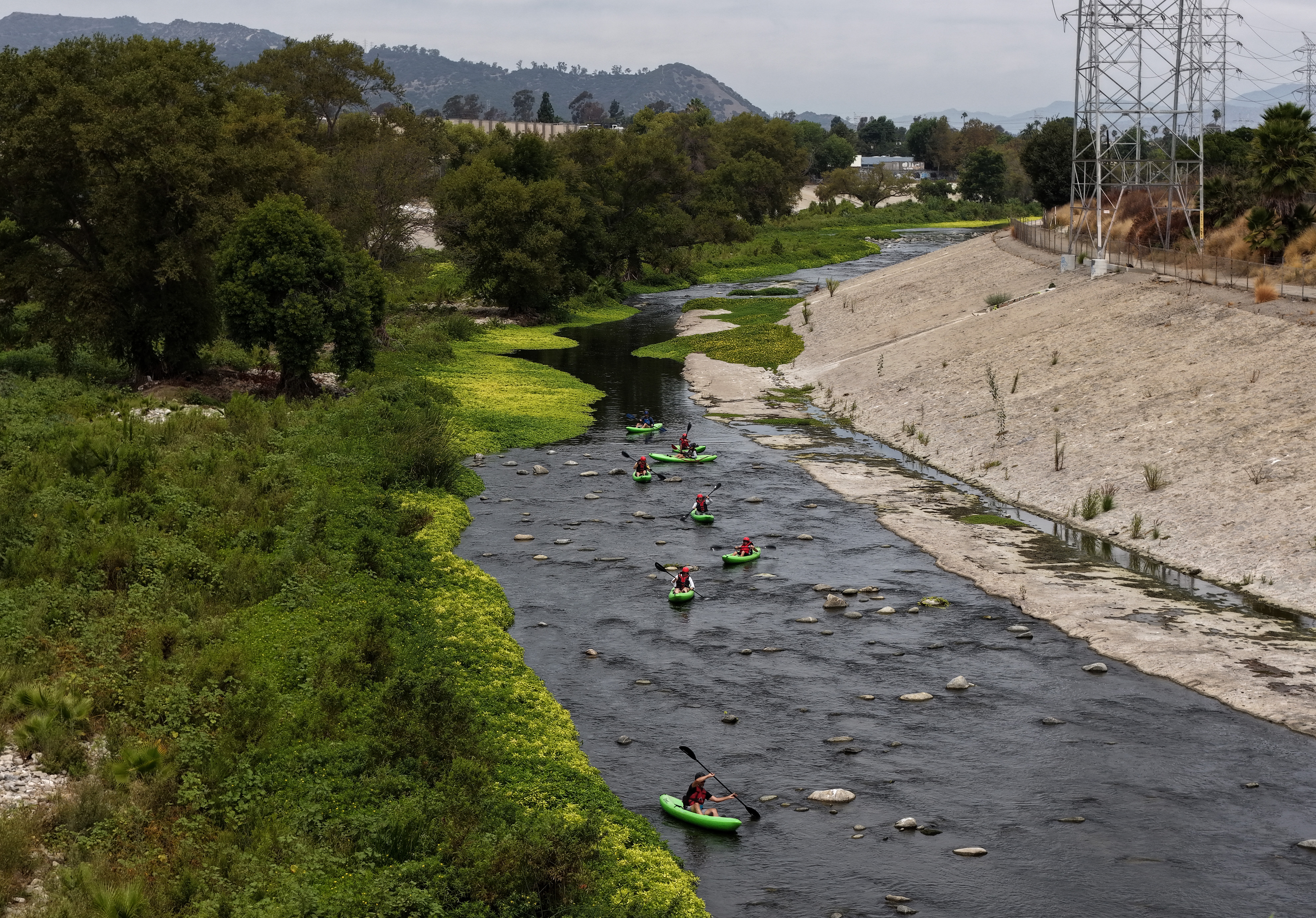 Kayakers navigate along an urban river.