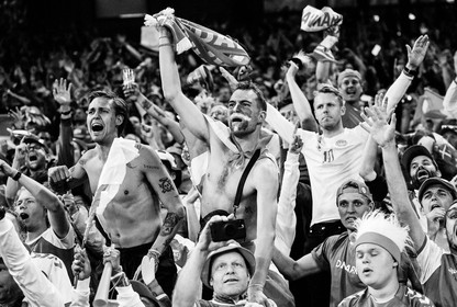 Black-and-white photo of Denmark’s fans celebrate the team’s victory after defeating Russia in a match