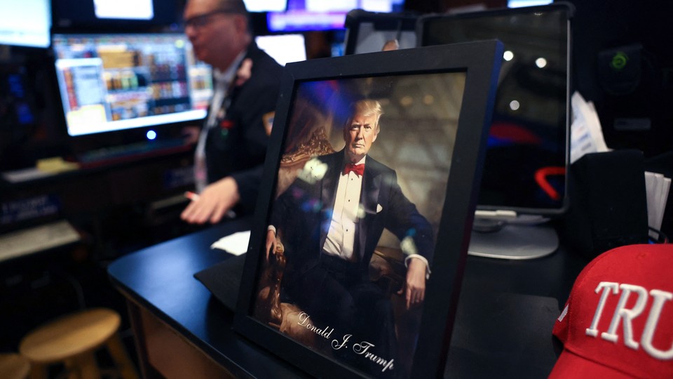 A photo of a framed portrait of Donald Trump and a Trump hat sitting on a desk at the New York Stock Exchange