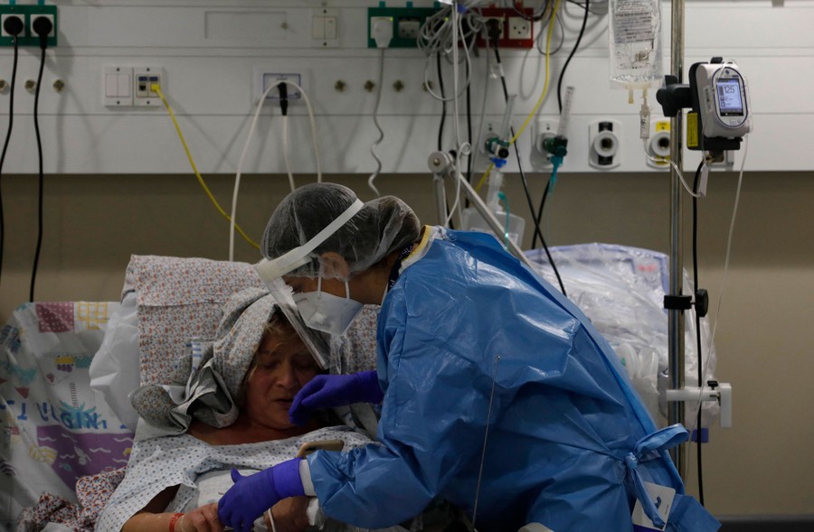 A medical worker tends to a COVID-19 patient in a hospital bed.