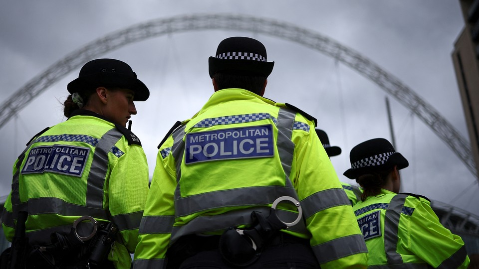 Photograph of three European police officers in neon jackets taken from behind