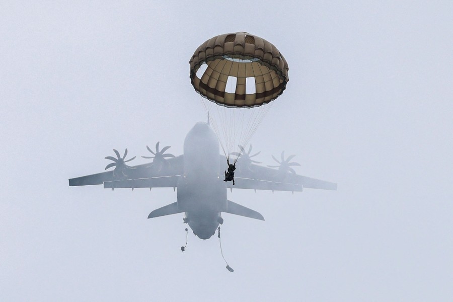 A paratrooper parachutes from a large aircraft