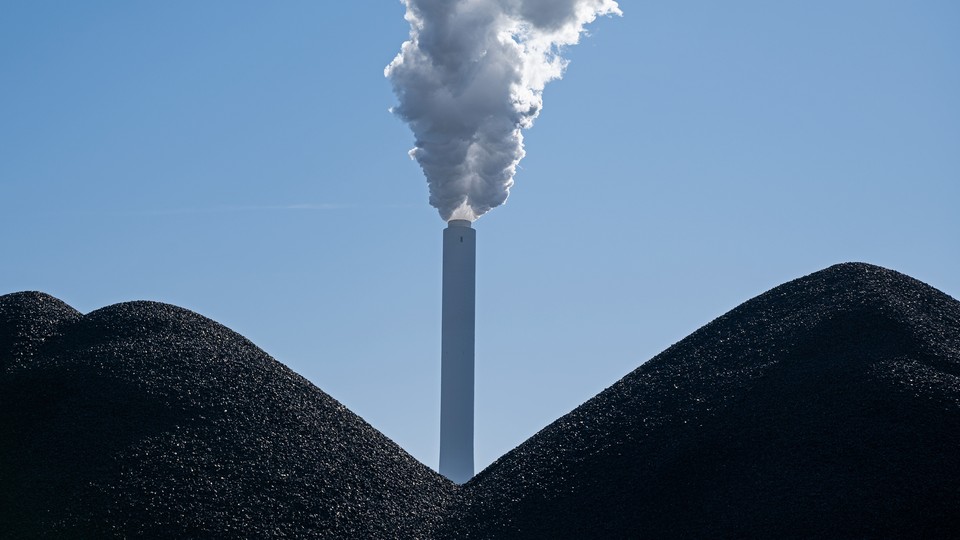 A smoking smokestack stands behind piles of coal at the coal-fired Onyx Kraftwerk Farge power plant.