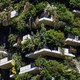 A photo of the outside of an apartment building with white balconies and greenery