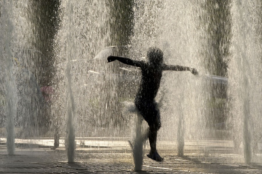 A boy leaps through fountains.