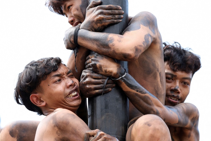 Several people try to climb a greased pole.