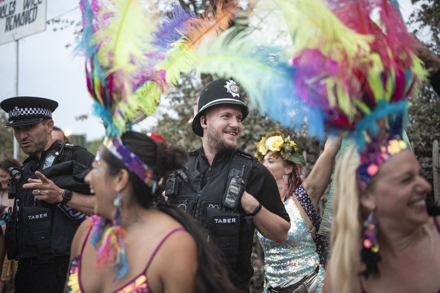 Costumed women dance beside uniformed police officers who are smiling.