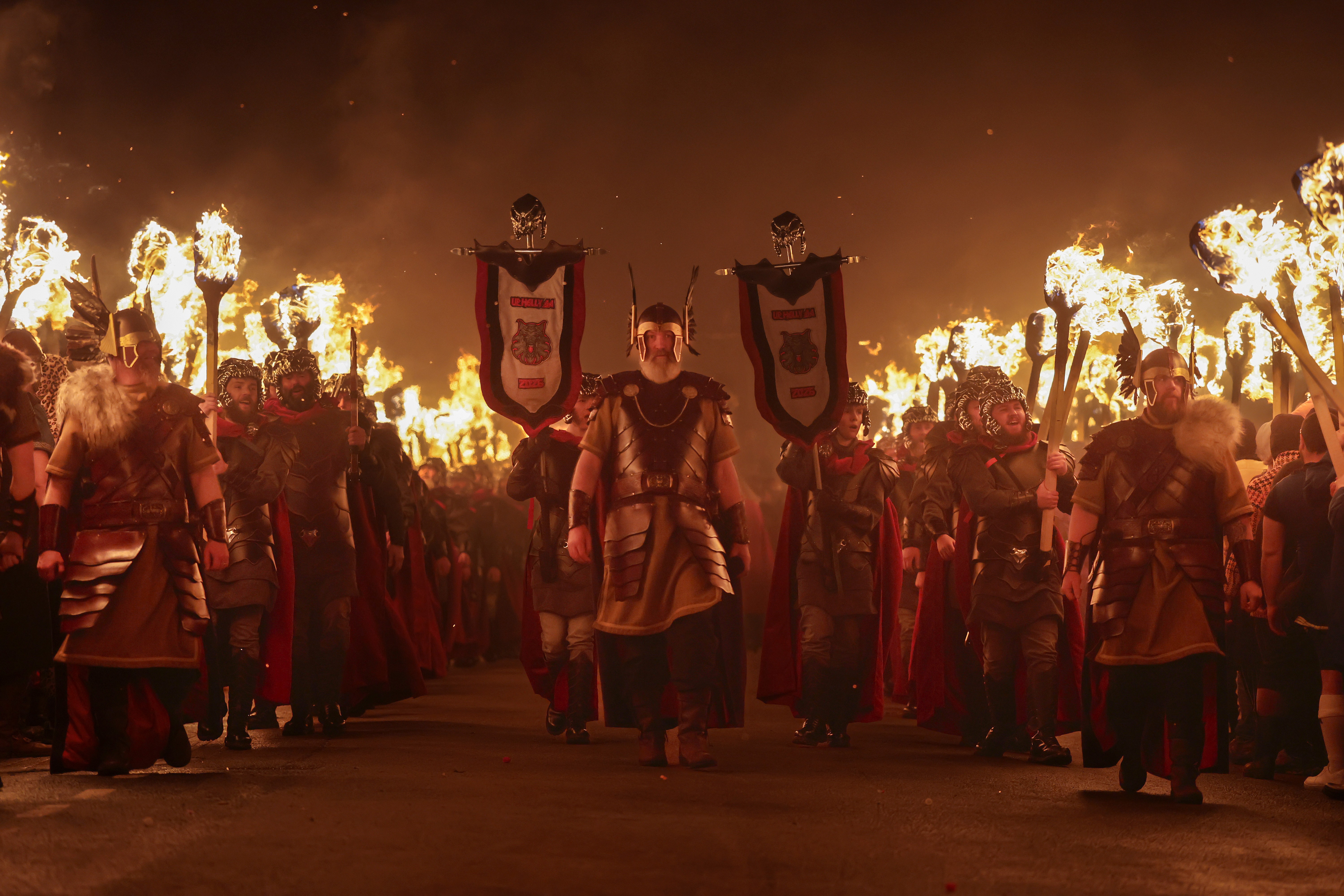 People dressed as Vikings, carrying torches, march during a parade.