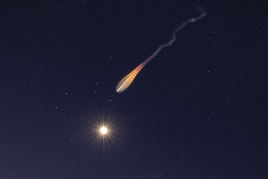 A launching rocket leaves a bright trail in the night sky.