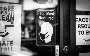 Signs requiring face masks and COVID-19 protocols on a restaurant window in Plymouth, Michigan