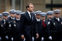 Emmanuel Macron walks past a line of police officers in formation during a ceremony to honor the four victims of the Paris police-headquarters killings.