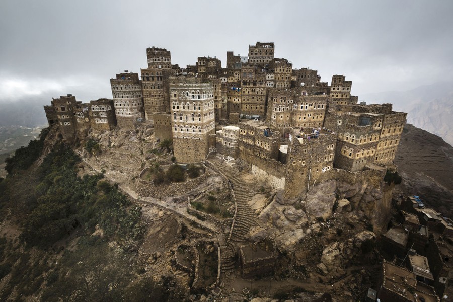 Tall stone buildings stand clustered close together on a rocky hilltop.