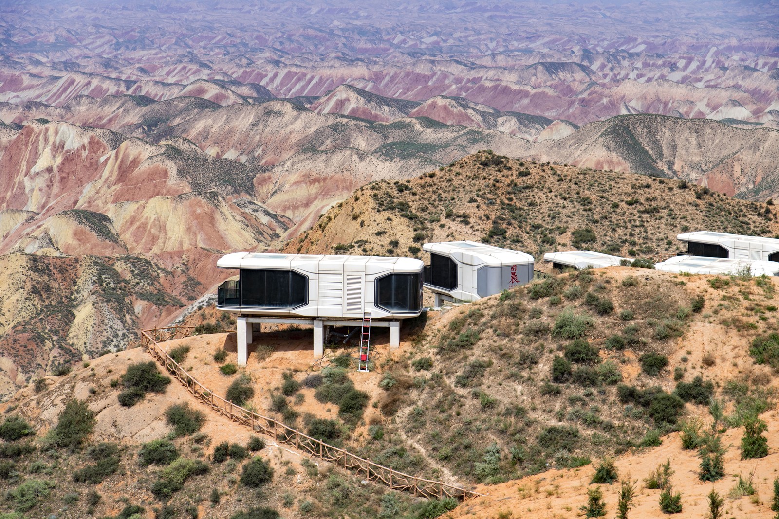 A set of futuristic-looking dwellings, mounted along a ridge overlooking desert hills.
