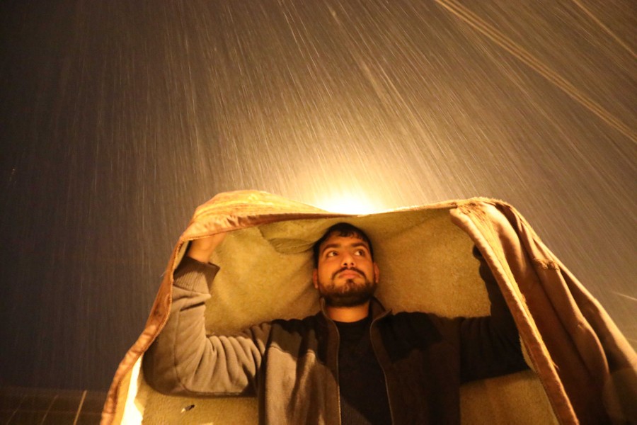 A man covers himself with blanket during heavy rain.