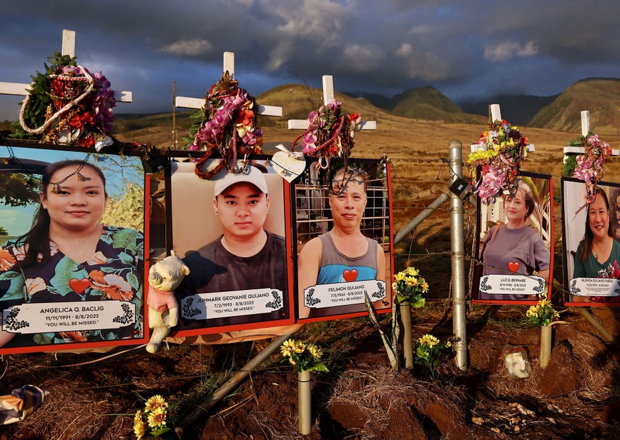 Portraits of loved ones and crosses are displayed at a public memorial.