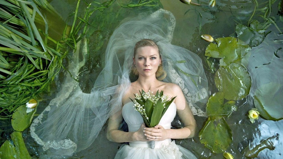 A still from Melancholia showing Kirsten Dunst in a wedding dress floating in a river