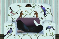 A person blending in with a couch, holding a book in front of their face