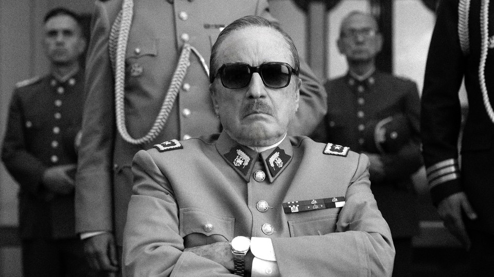 Jaime Vadell wearing sunglasses and a military uniform with arms crossed