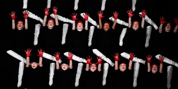 Dancers wearing white boots and red gloves perform on a stage.