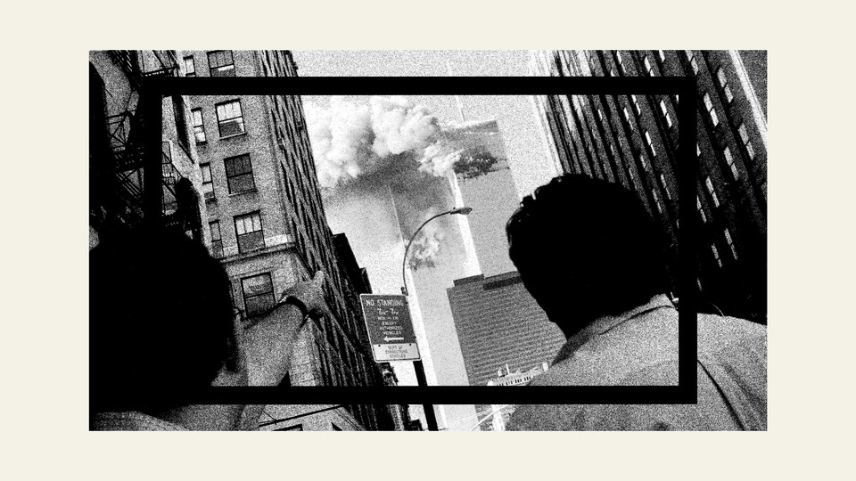 A black-and-white image of the back of two people's heads as they watch smoke coming out of the World Trade Center's Twin Towers during 9/11