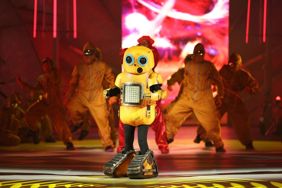A performer appears onstage wearing a robot costume.