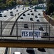 A "Yes on 50!" sign hangs over a freeway in California as cars drive below.