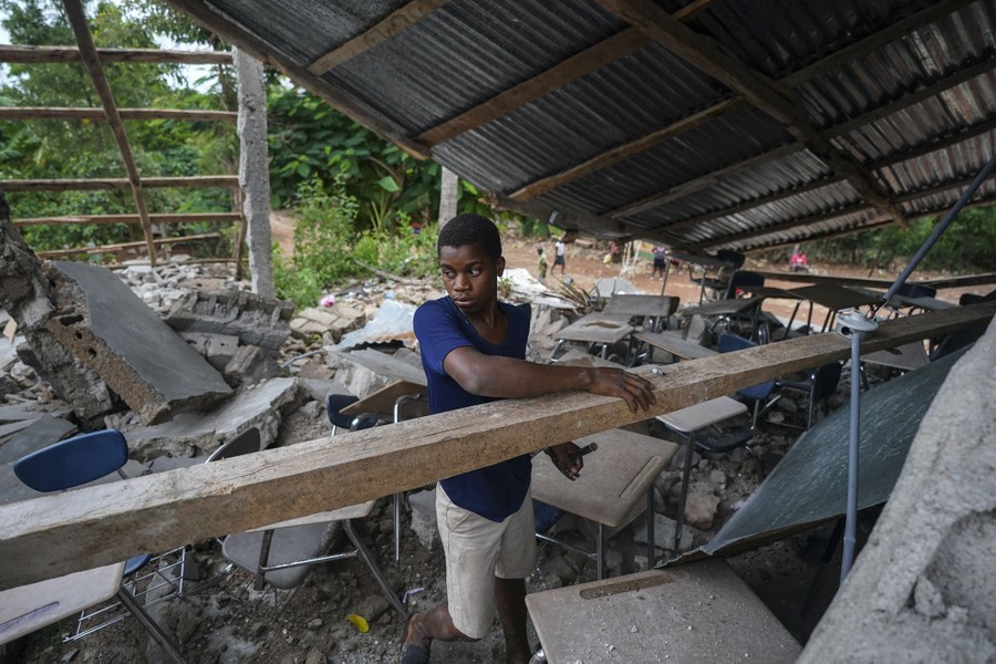 A man tries to recover usable materials from a collapsed building.