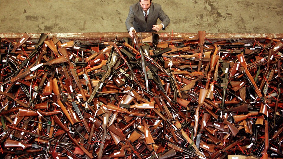 An overhead view of a man standing in front of a huge pile of rifles