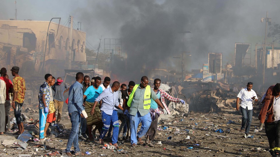 Civilians carry the dead body of an unidentified man from the scene of an explosion.