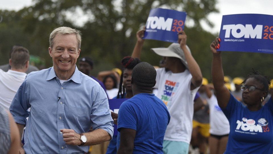 Tom Steyer arrives at the Charleston Blue Jamboree. He's flanked by supporters holding "Tom 2020" signs.