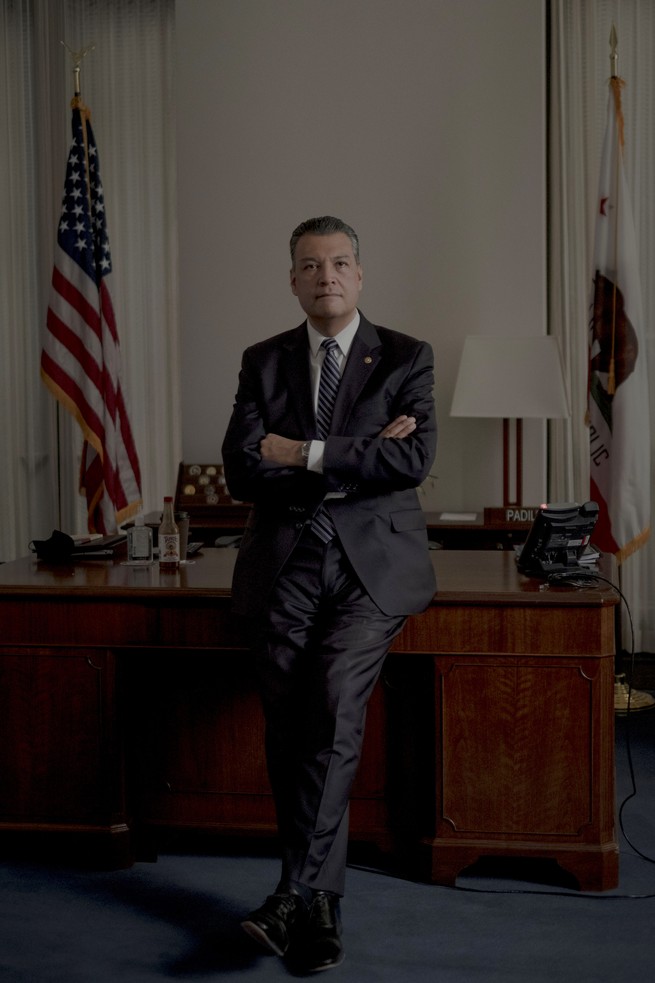 Alex Padilla leaning against his desk with his arms and legs crossed