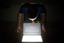A man on his computer in a dark room