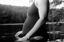 Black-and-white photo of a pregnant person entering a body of water