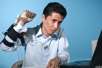 A man raises his hand, which is covered in a glove and wires