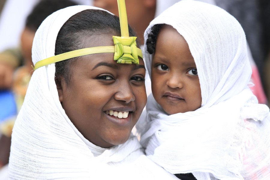 A woman holds a child during a religious celebration.