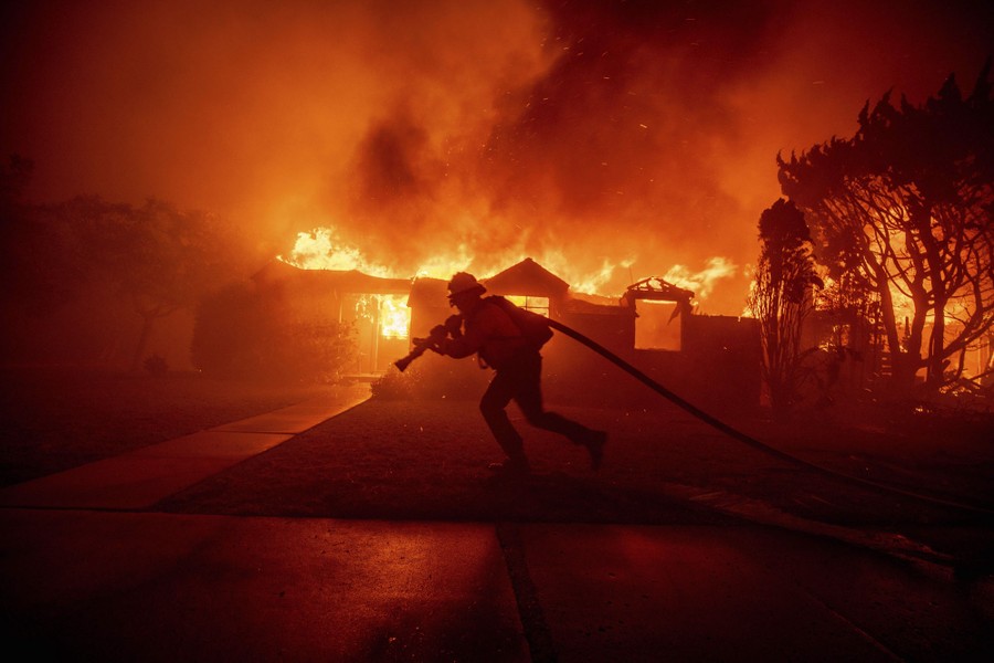 A firefighter battles the Palisades Fire as it consumes a building in Pacific Palisades on January 7, 2025.