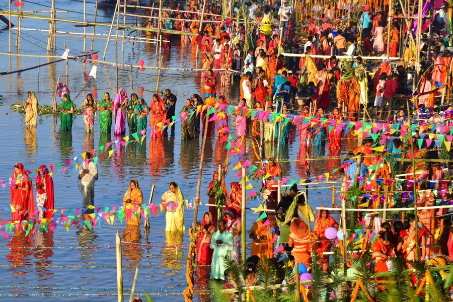 Shumë rreshta njerëzish mblidhen brenda dhe përgjatë një lumi të cekët.