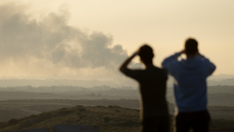 People looking at smoke over the Gaza Strip