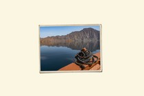 An illustration of a printed photo of a boat rope sitting in front of a body of water and a mountain.