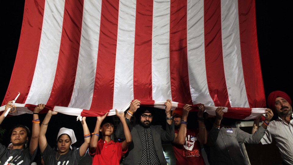Sikh mourners holding up a large American flag