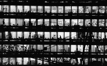 Black-and-white picture of office building, with windows showing silhouettes of people working
