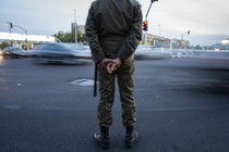 An Iranian police officer stands at a busy traffic intersection.