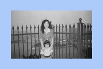 The author as a child with her mother near a gate, in black-and-white