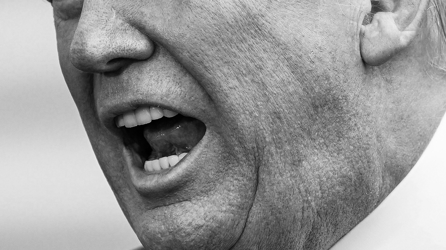 Una foto en blanco y negro de la mitad inferior del rostro de Trump mientras habla.