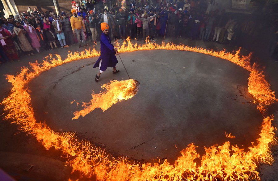 A person swings a fireball on a chain, standing in a circle of fire.