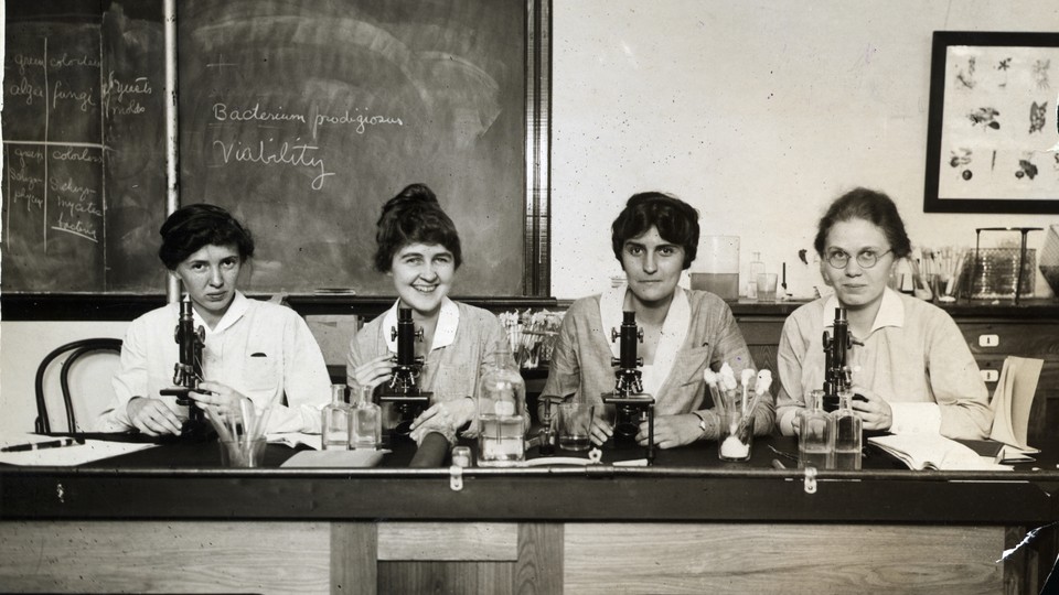 Women seated before microscopes in an undated photo