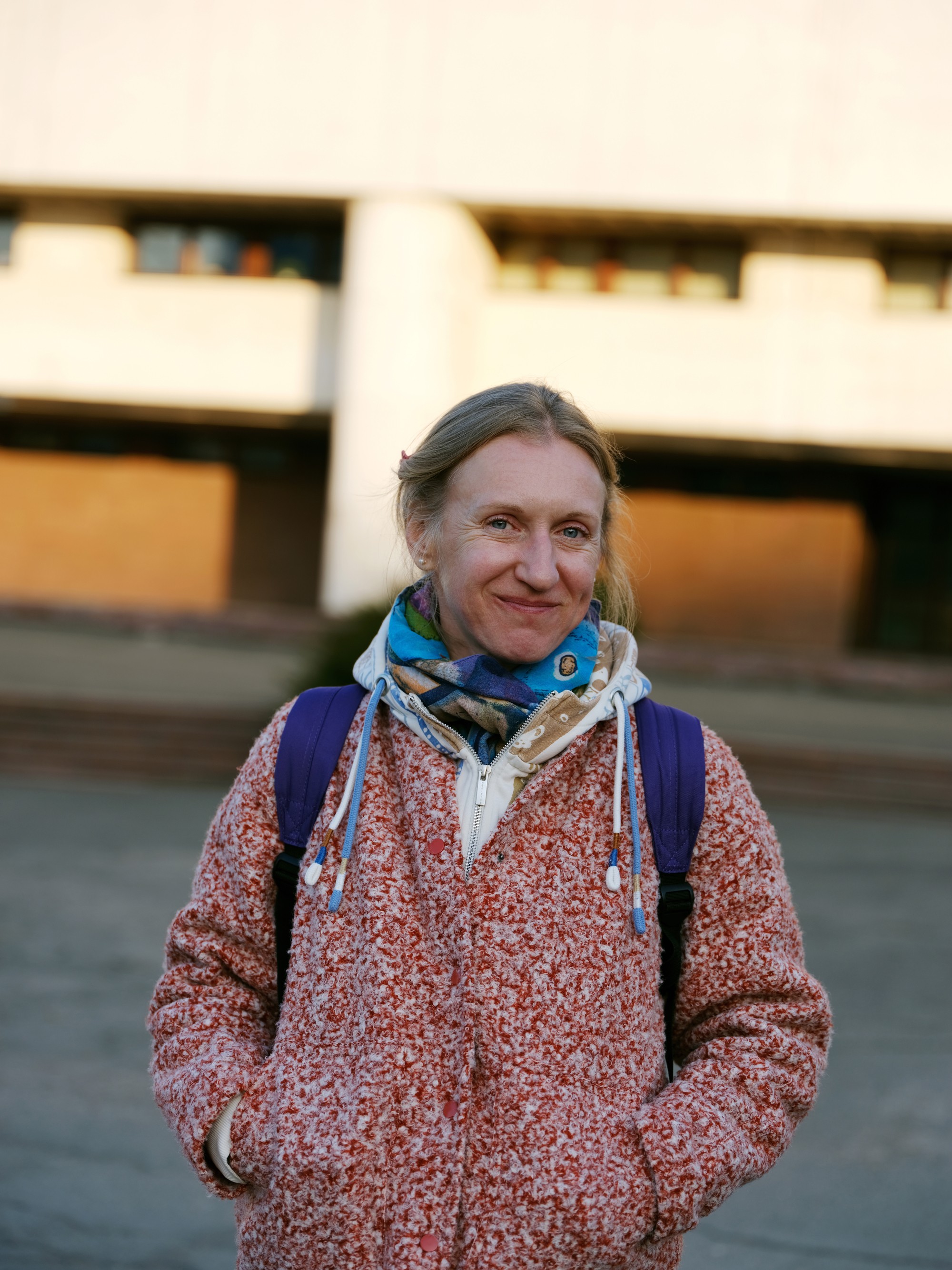 photo of smiling woman in red coat with hands in pockets