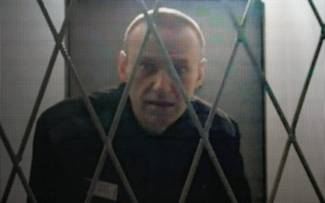 Navalny, behind a security fence, looking at the camera